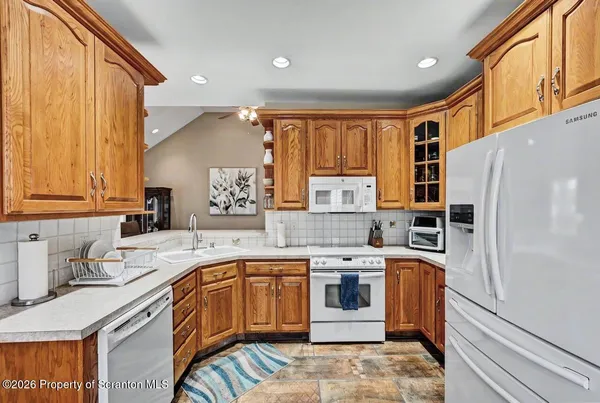 a kitchen with stainless steel appliances granite countertop a sink a stove a refrigerator a dining table and chairs with wooden floor