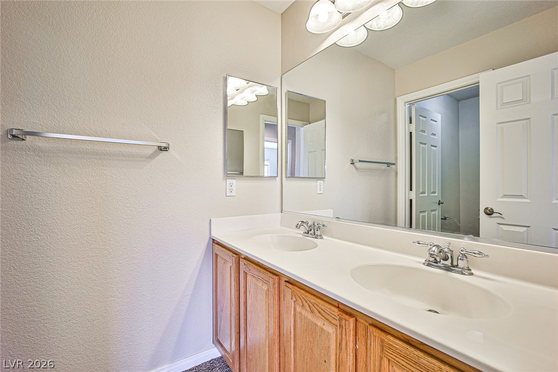 8022 Diamond Gorge Road Las Vegas, NV 89178 - Photo 20 of 37 Double sinks accent a wood vanity under a large wall mirror.