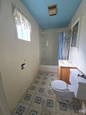 a bathroom with a sink a toilet a window and shower