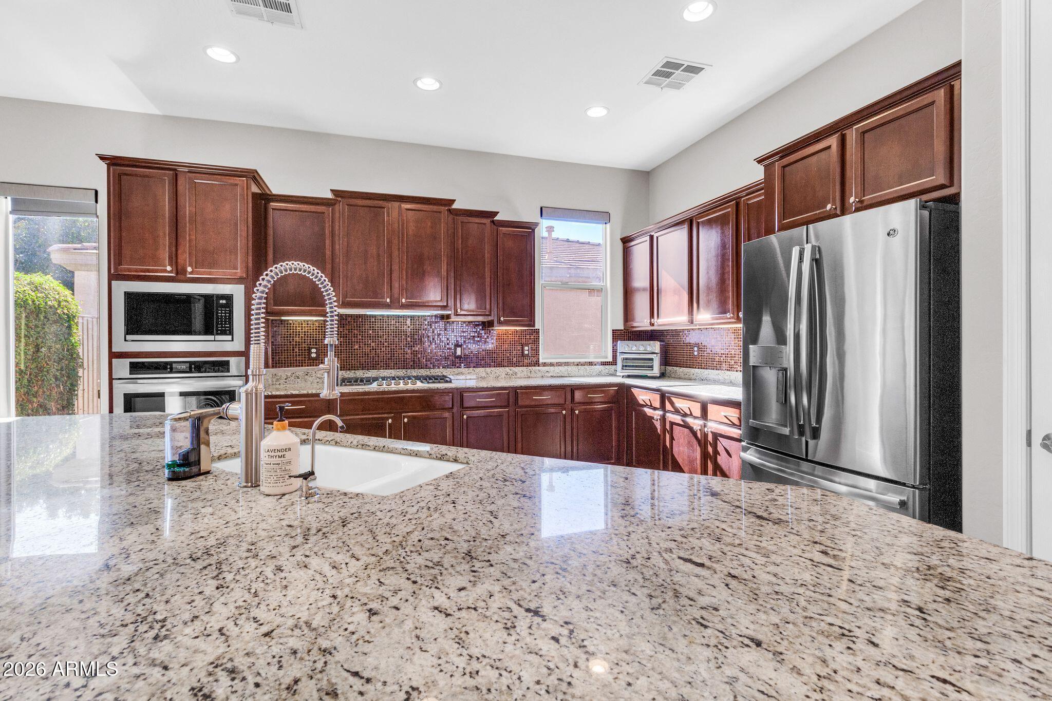 5333 South Marigold Way Gilbert, AZ 85298 - Photo 10 of 69 a kitchen with stainless steel appliances granite countertop a refrigerator sink and stove