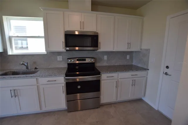 a kitchen with white cabinets and a stove top oven