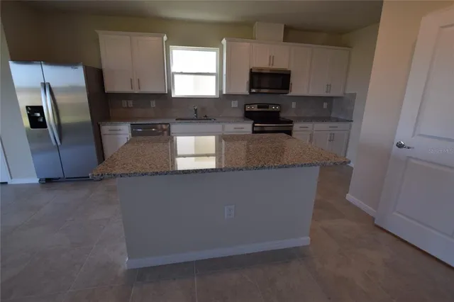 a kitchen with stainless steel appliances granite countertop a refrigerator a stove a sink a microwave and white cabinets