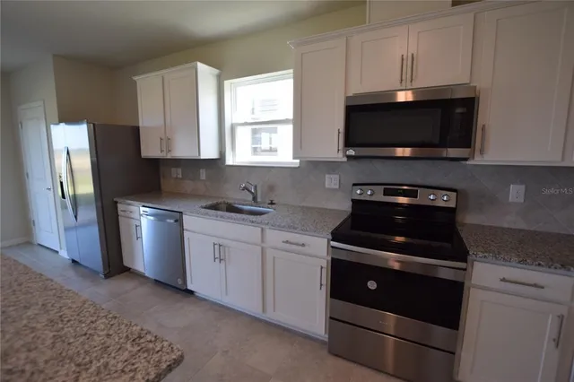 a kitchen with stainless steel appliances a stove a microwave a sink and cabinets