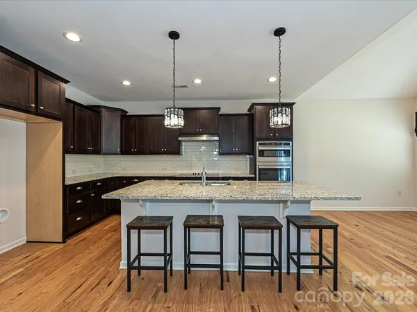 a kitchen with stainless steel appliances granite countertop a stove a refrigerator a oven a sink with a dining table and chairs