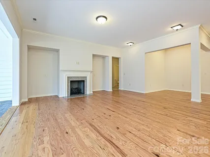 a view of empty room with wooden floor and fireplace