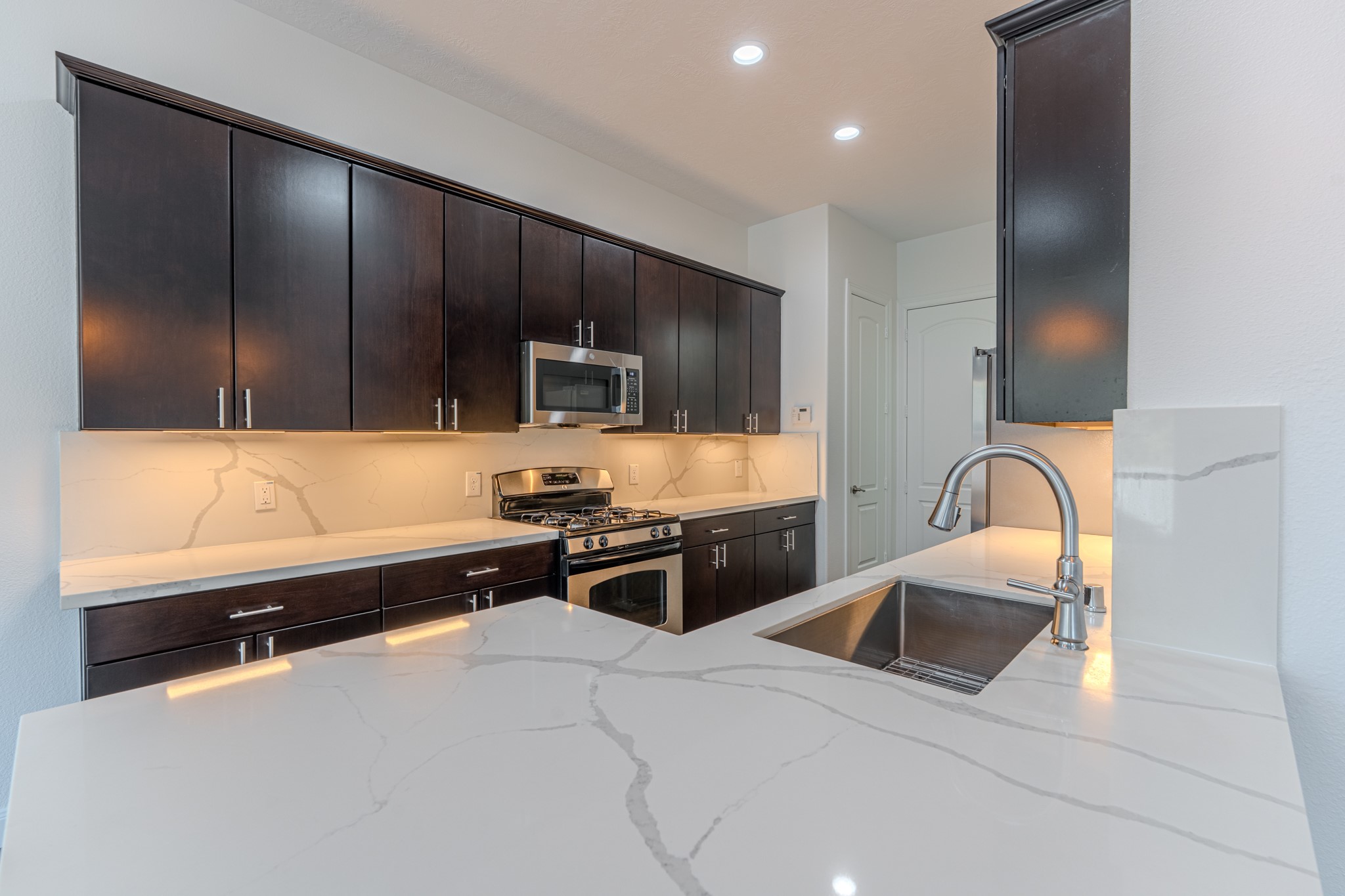 58 Aventura Place Spring, TX 77389 - Photo 25 of 50 a kitchen with granite countertop wooden cabinets a stove and a refrigerator