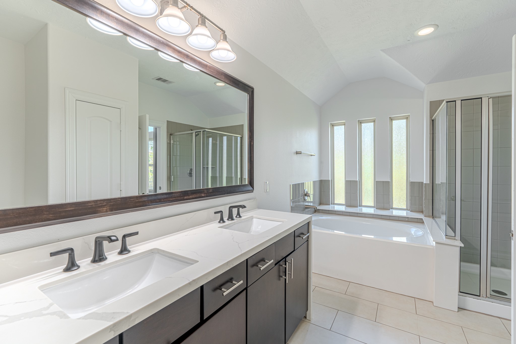 58 Aventura Place Spring, TX 77389 - Photo 36 of 50 Spa-like primary bath with dual vanities, soaking tub, and separate glass-enclosed shower.