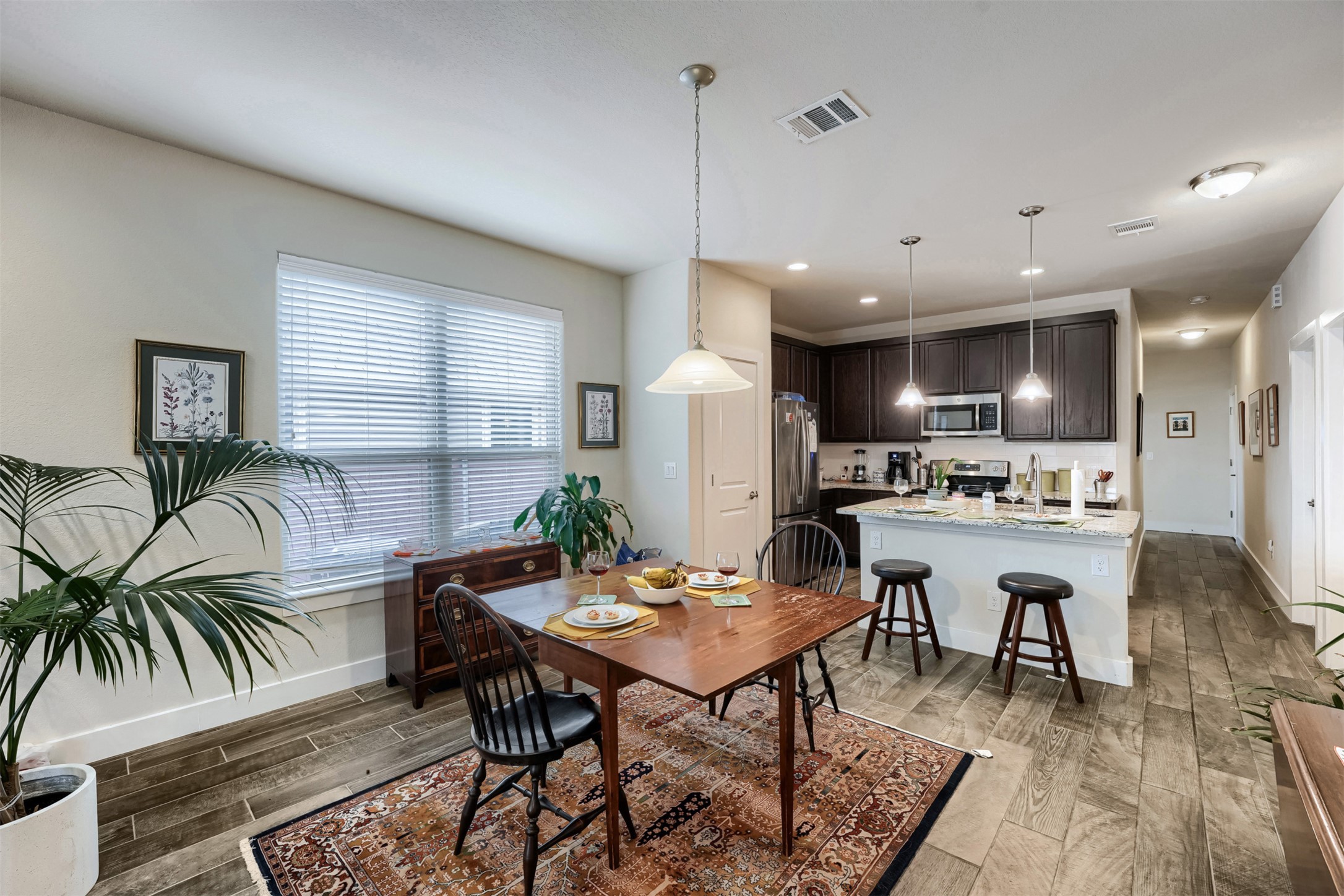 418 High Tech Drive Georgetown, TX 78626 - Photo 8 of 34 Open-concept living space featuring wood-finish flooring, a kitchen island with seating, dark wood cabinetry, stainless steel appliances, and recessed lighting