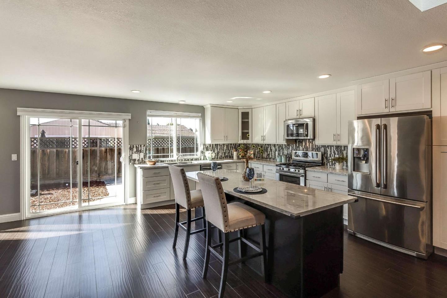 36045 Haley Street Newark, CA 94560 - Photo 12 of 26 a kitchen with a dining table chairs refrigerator and cabinets