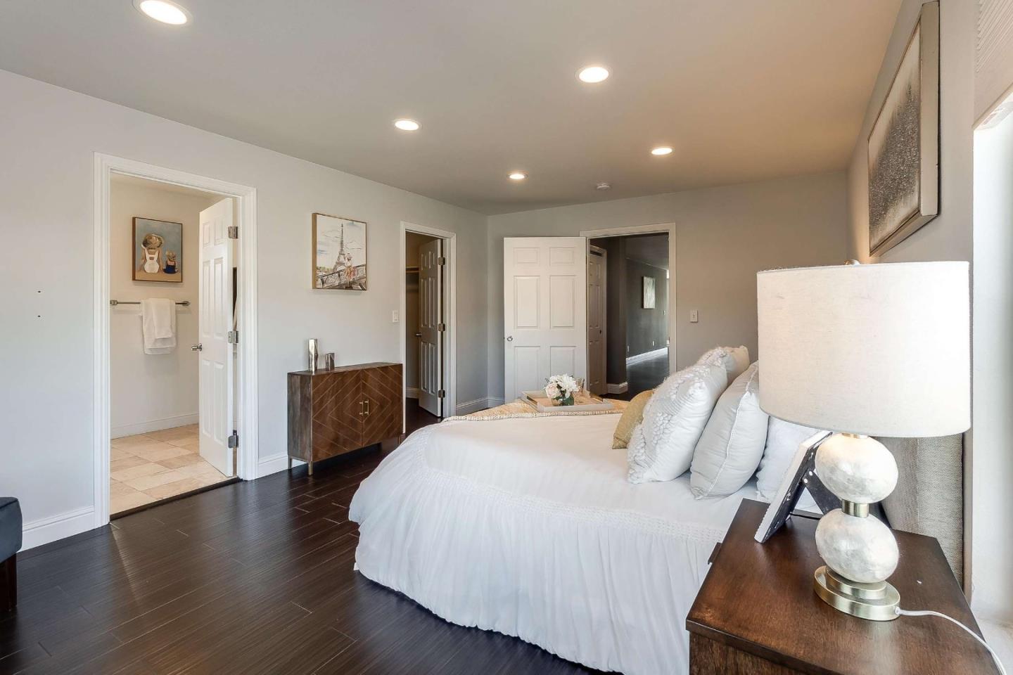36045 Haley Street Newark, CA 94560 - Photo 17 of 26 a spacious bedroom with a bed and a lamp