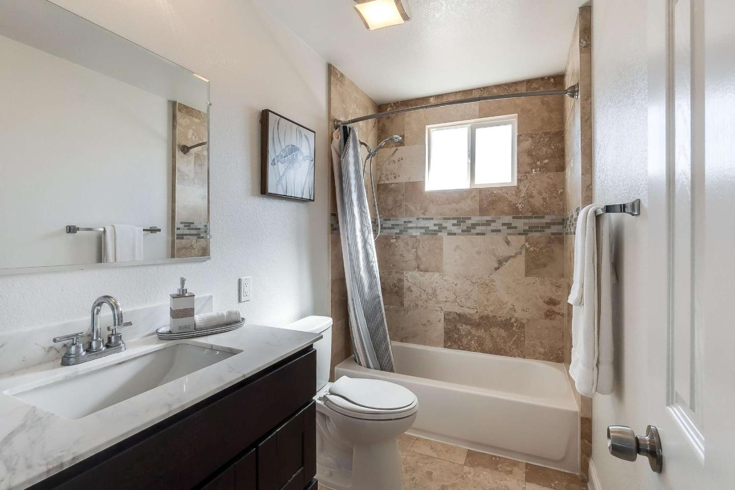36045 Haley Street Newark, CA 94560 - Photo 23 of 26 a bathroom with a bathtub shower sink vanity mirror and toilet