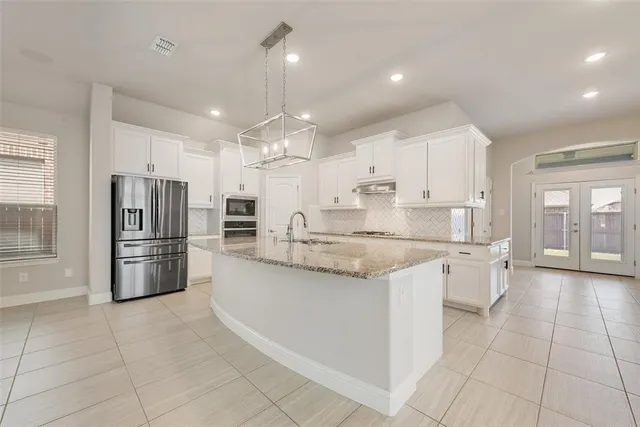 a large kitchen with granite countertop a large counter top stainless steel appliances and cabinets