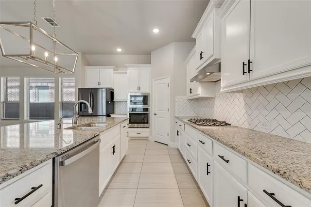 a kitchen with stainless steel appliances granite countertop a sink dishwasher and white cabinets with a dining table