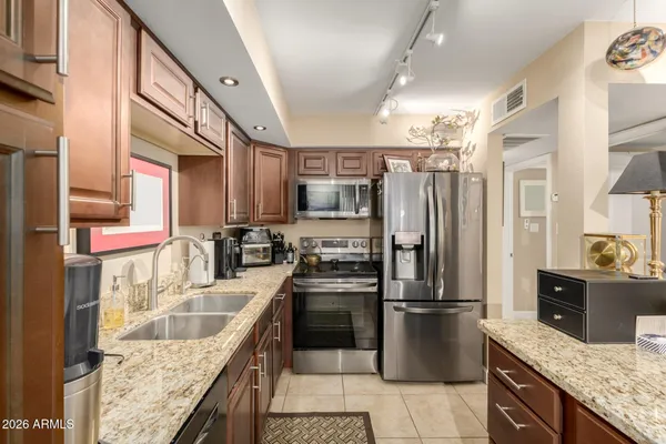 a kitchen with stainless steel appliances granite countertop a refrigerator a stove top oven and sink