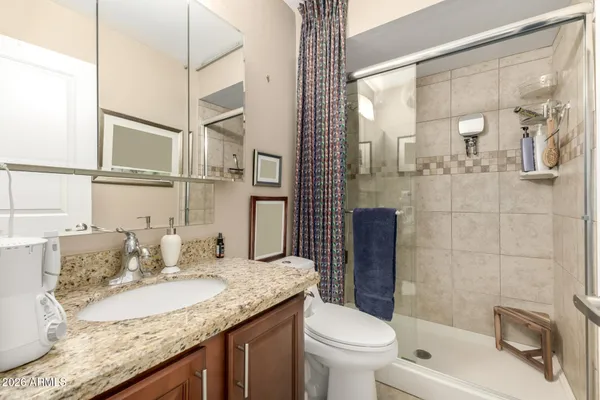 a bathroom with a granite countertop sink a toilet a mirror and shower
