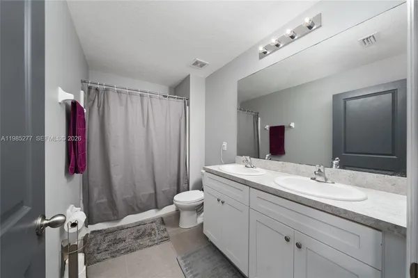 a view of a white house with a big yard potted plants and a table