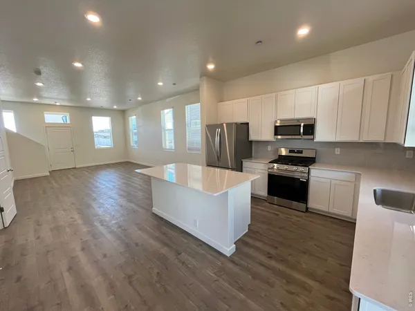 a large kitchen with stainless steel appliances wooden floors and white cabinets