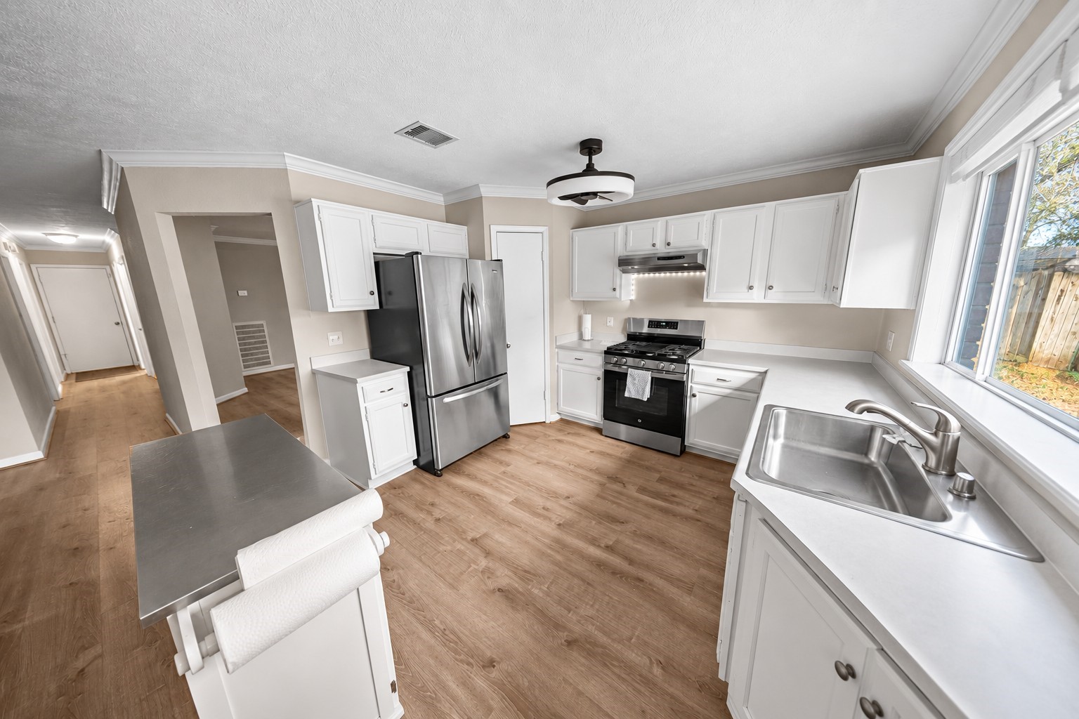 9107 Towerstone Court Spring, TX 77379 - Photo 12 of 42 Bright kitchen with modern appliances, white cabinetry, and a cozy island. Large windows offer natural light and a view of the backyard, creating a welcoming atmosphere.