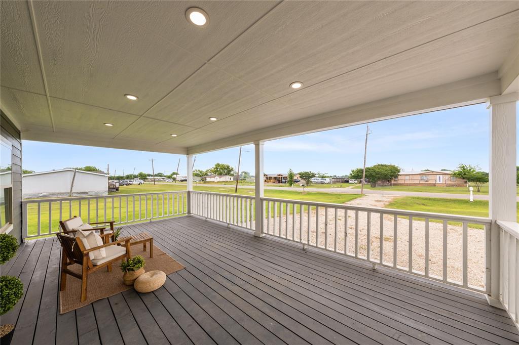 1128 Newton Road Ferris, TX 75125 - Photo 24 of 28 Expansive covered porch featuring grey wood-finish decking, recessed lighting, white railing, and structural support columns