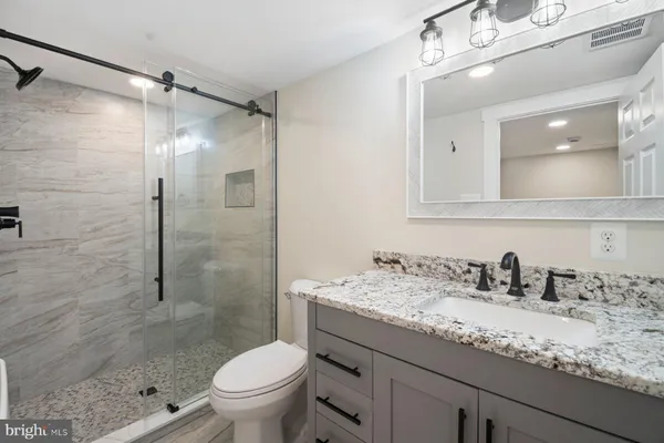 a bathroom with a granite countertop sink toilet and shower