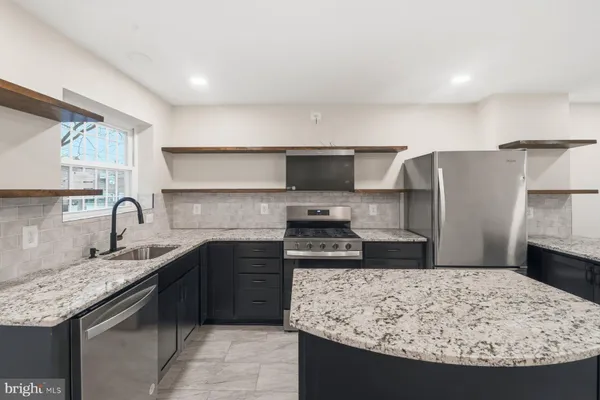 a kitchen with stainless steel appliances granite countertop a sink stove and refrigerator