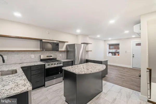 a large kitchen with stainless steel appliances kitchen island granite countertop a stove a sink dishwasher and a refrigerator with wooden floor