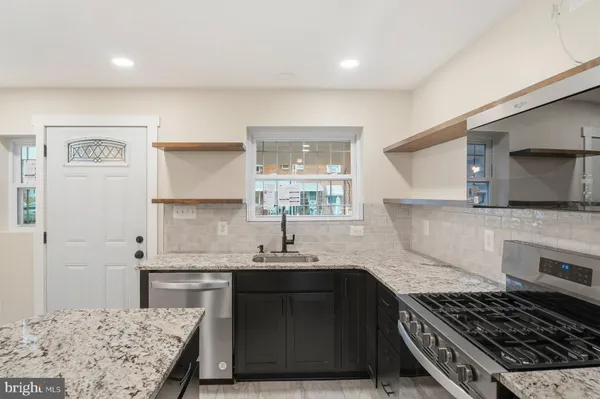 a kitchen with kitchen island granite countertop a sink cabinets and stainless steel appliances