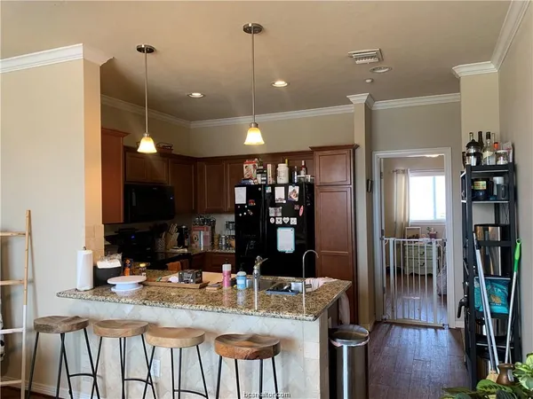a kitchen with kitchen island granite countertop a table chairs refrigerator and sink
