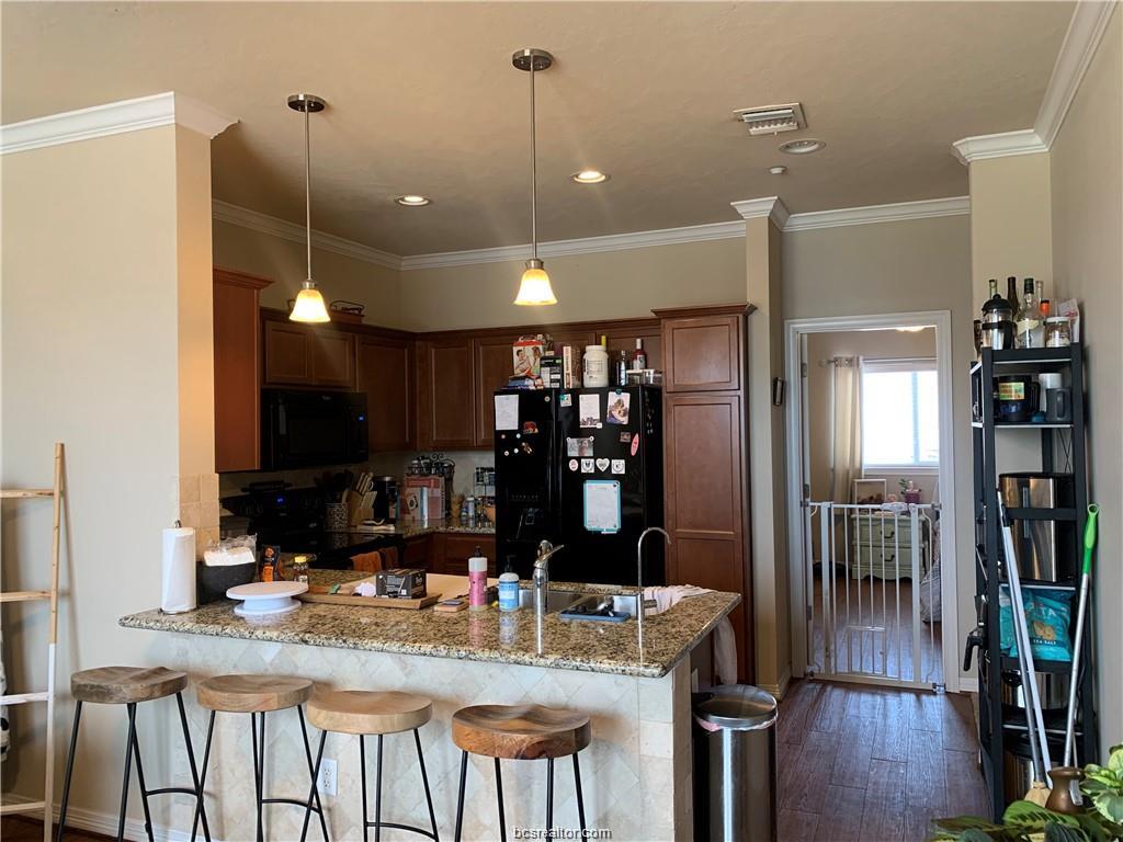 1198 Jones-Butler Road, Unit 1509 College Station, TX 77840 - Photo 2 of 8 a kitchen with kitchen island granite countertop a table chairs refrigerator and sink