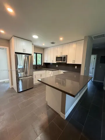 a large kitchen with stainless steel appliances lots of counter space and wooden floor