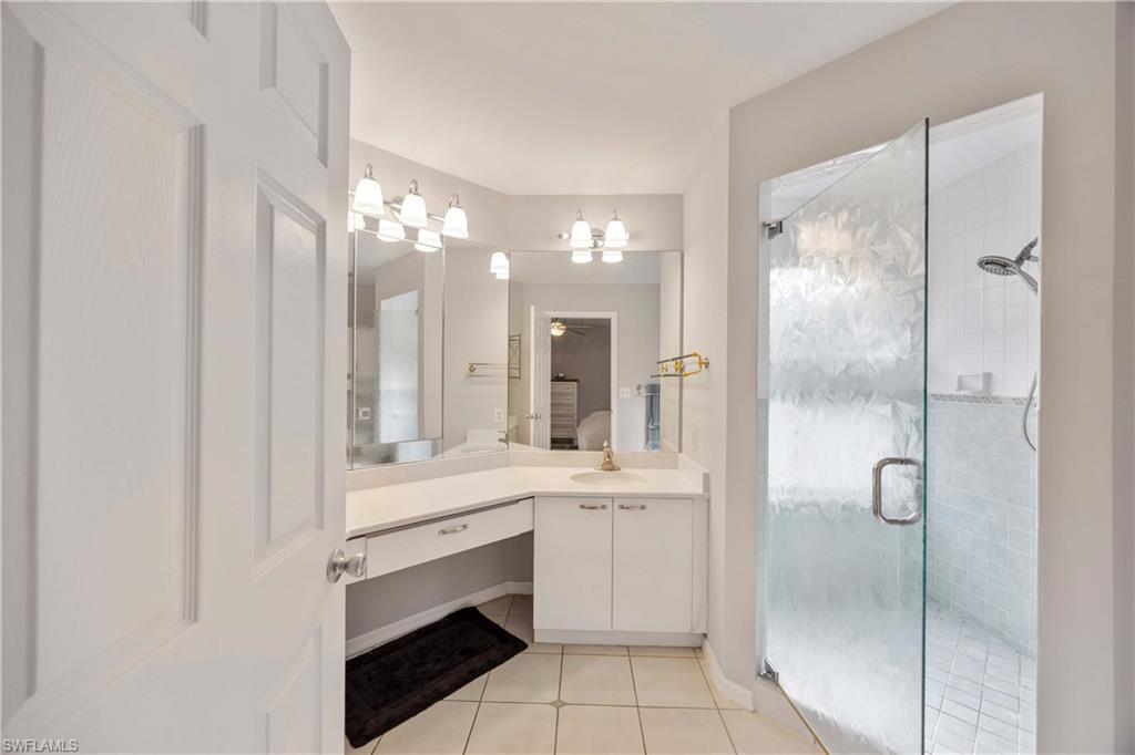 2860 Citrus Lake Drive, Unit R204 Naples, FL 34109 - Photo 11 of 32 Bathroom with tile patterned flooring, vanity, a shower with door, and a notable chandelier