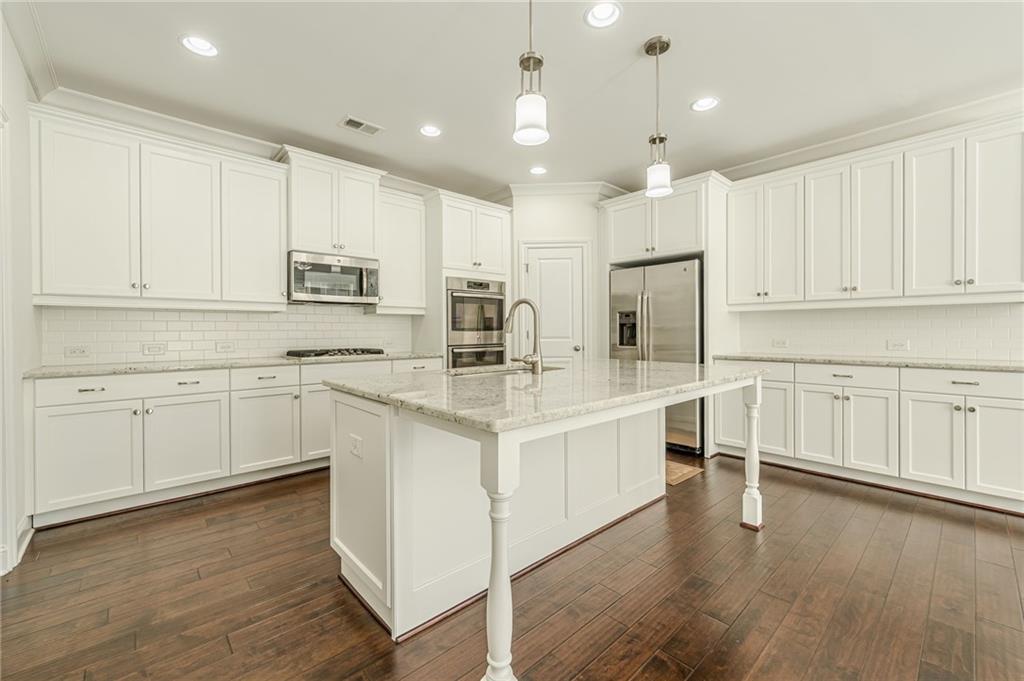 1040 Peyton View Court Alpharetta, GA 30004 - Photo 22 of 53 a kitchen with kitchen island granite countertop white cabinets and white appliances