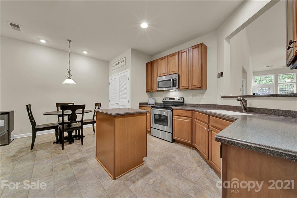 107 Inlet Point Drive Tega Cay, SC 29708 - Photo 4 of 24 a kitchen with stainless steel appliances granite countertop a stove a sink a microwave a dining table and chairs