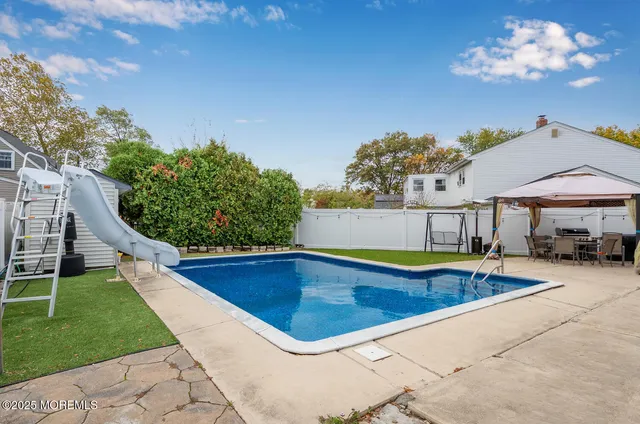 a view of a swimming pool with lawn chairs under an umbrella