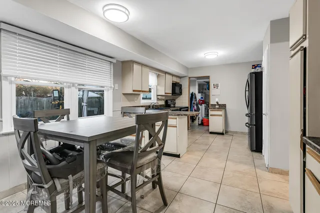 a kitchen with stainless steel appliances kitchen island granite countertop a refrigerator a stove a sink a dining table and chairs