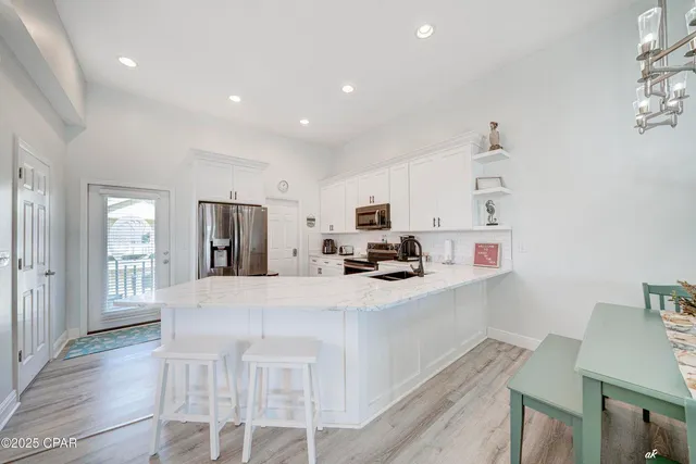 a kitchen with stainless steel appliances a sink a stove a refrigerator cabinets and a dining table