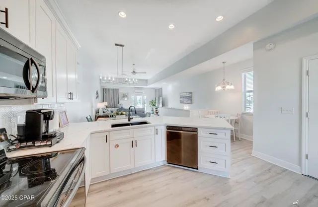 a kitchen with stainless steel appliances granite countertop a stove top oven a sink dishwasher and a microwave oven with white cabinets