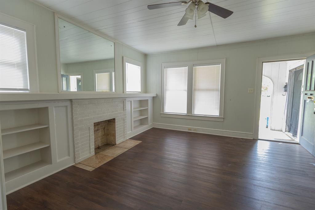 2913 Homan Avenue, Unit 2913 Waco, TX 76707 - Photo 4 of 16 Living area featuring a brick fireplace surround with a stone hearth, built-in shelving, wood-finish flooring, and a ceiling fan