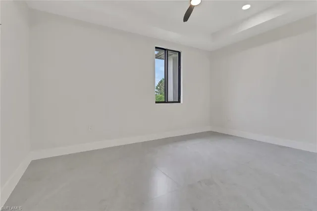 an empty room with a window and ceiling fan