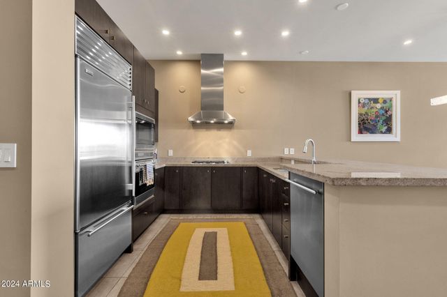 a kitchen with stainless steel appliances granite countertop a refrigerator a sink and a stove