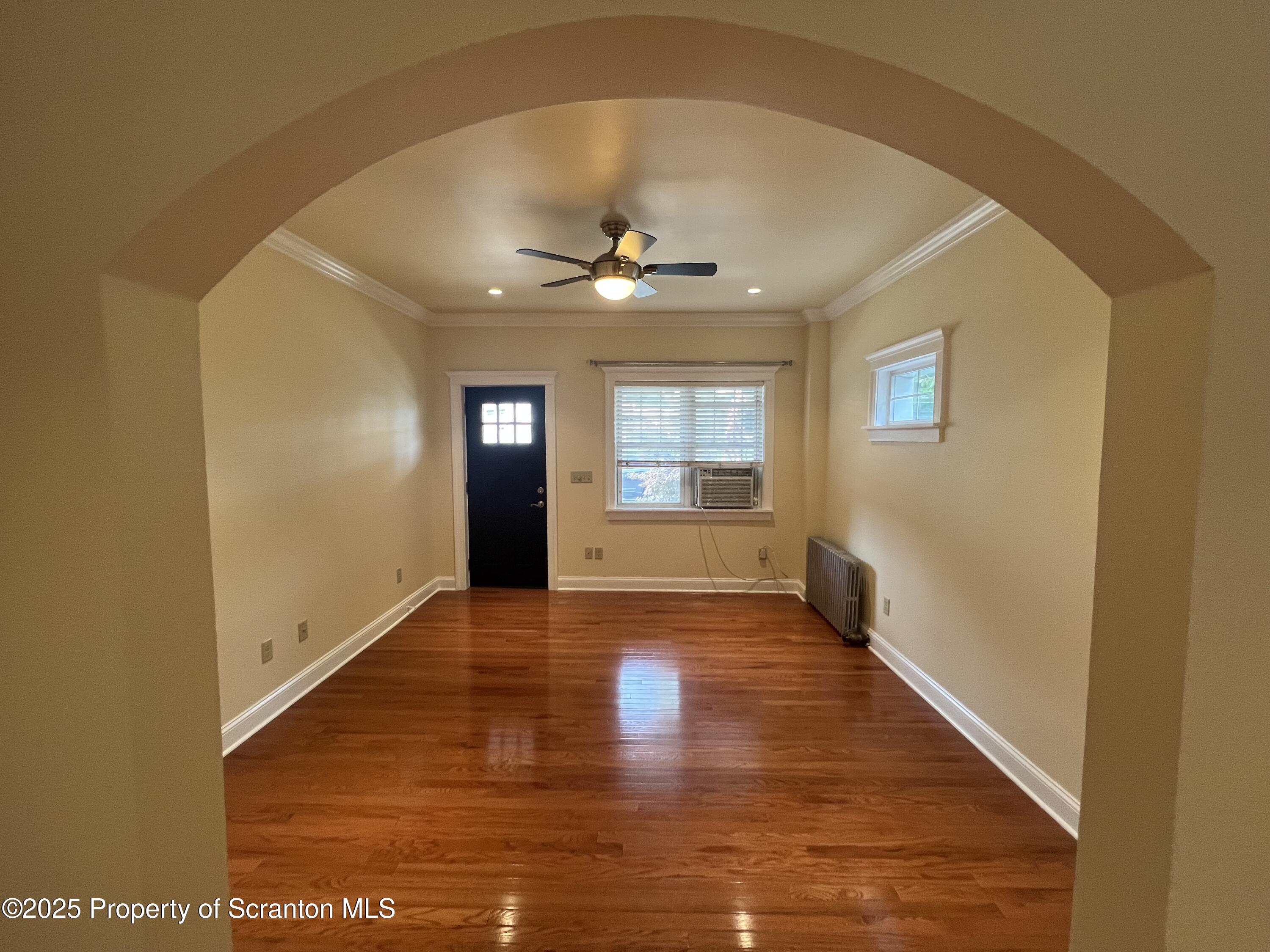 a view of an empty room with window and wooden floor