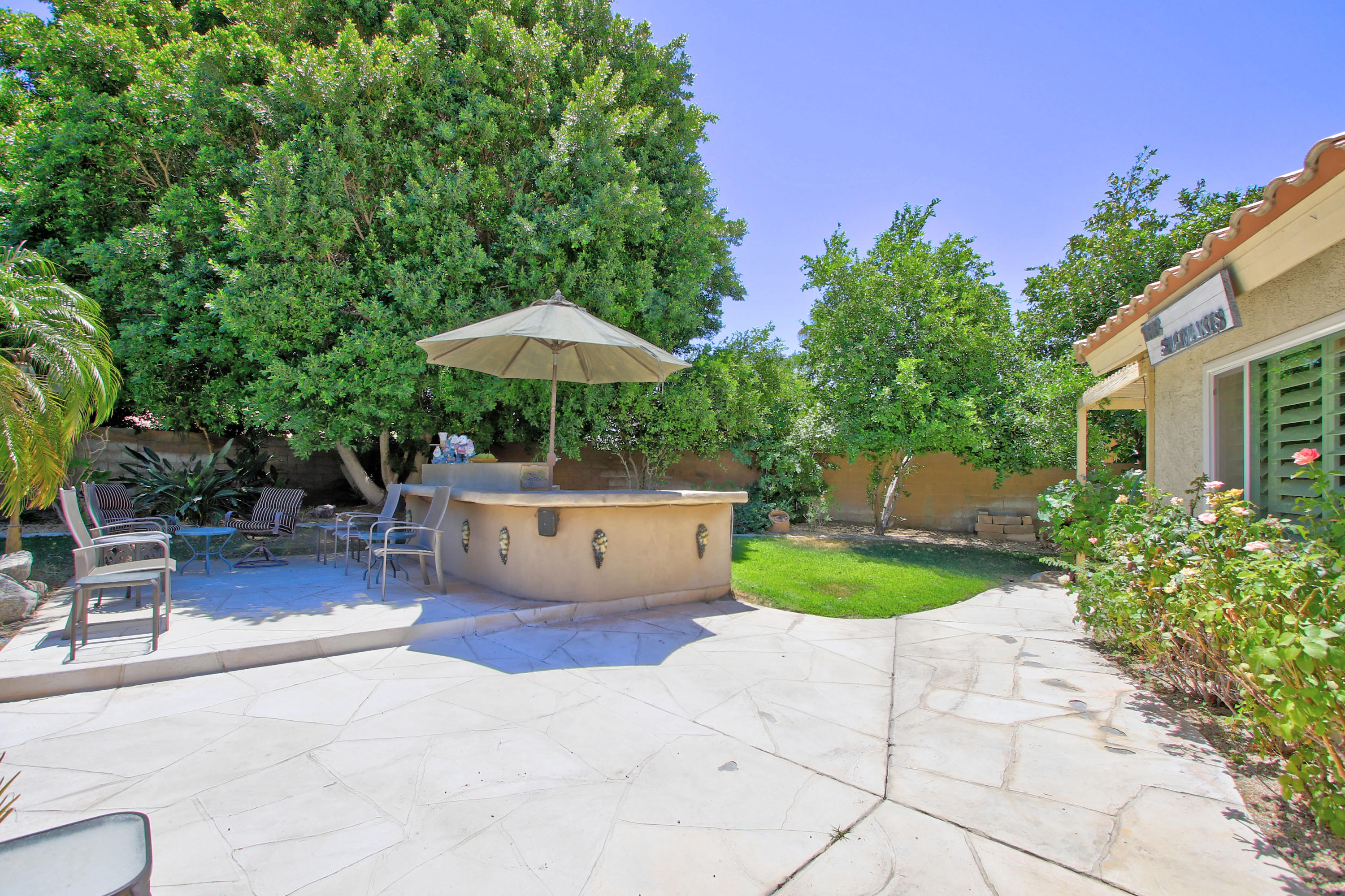 39730 Regency Way Palm Desert, CA 92211 - Photo 11 of 35 a view of a backyard with plants and a table and chairs under an umbrella