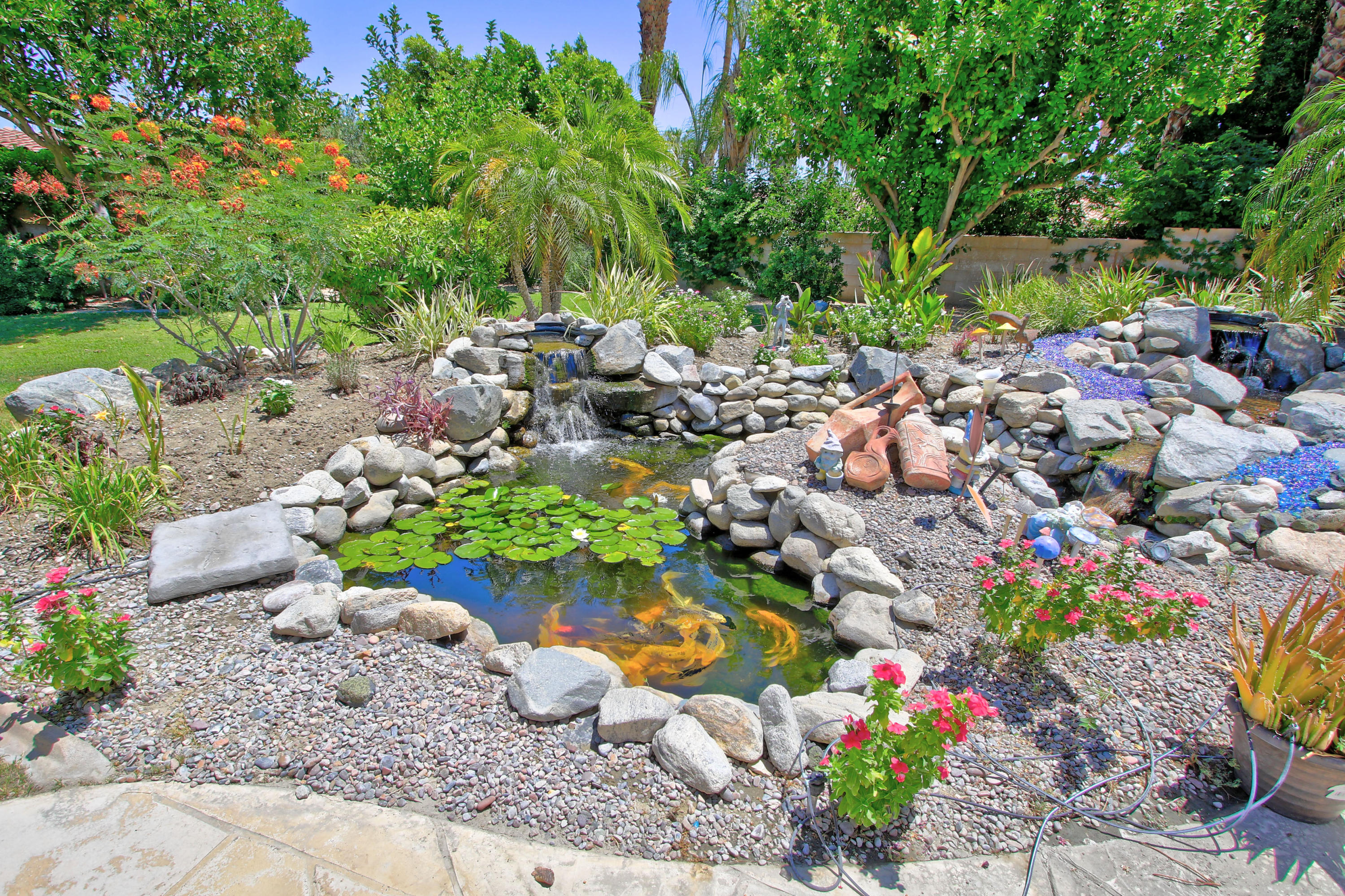 39730 Regency Way Palm Desert, CA 92211 - Photo 10 of 35 a garden with lots of trees and flowers and covered with wooden fence