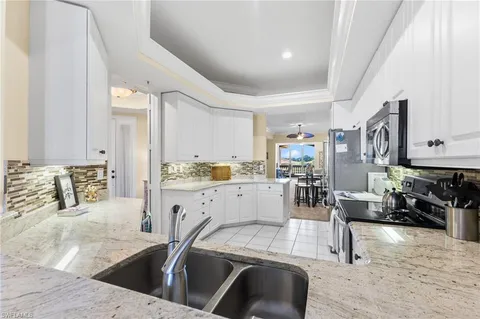 a kitchen with stainless steel appliances kitchen island granite countertop a stove and white cabinets