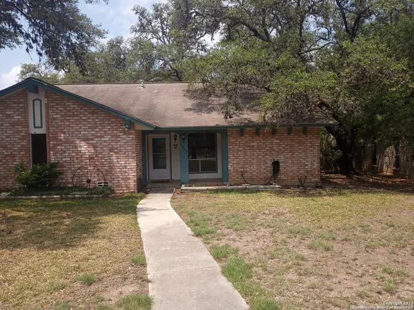 a front view of a house with a garden and trees