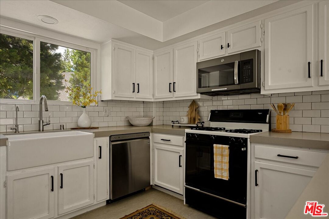 27975 St Bernard Lane Lake Arrowhead, CA 92352 - Photo 14 of 45 a kitchen with white cabinets and a stove top oven