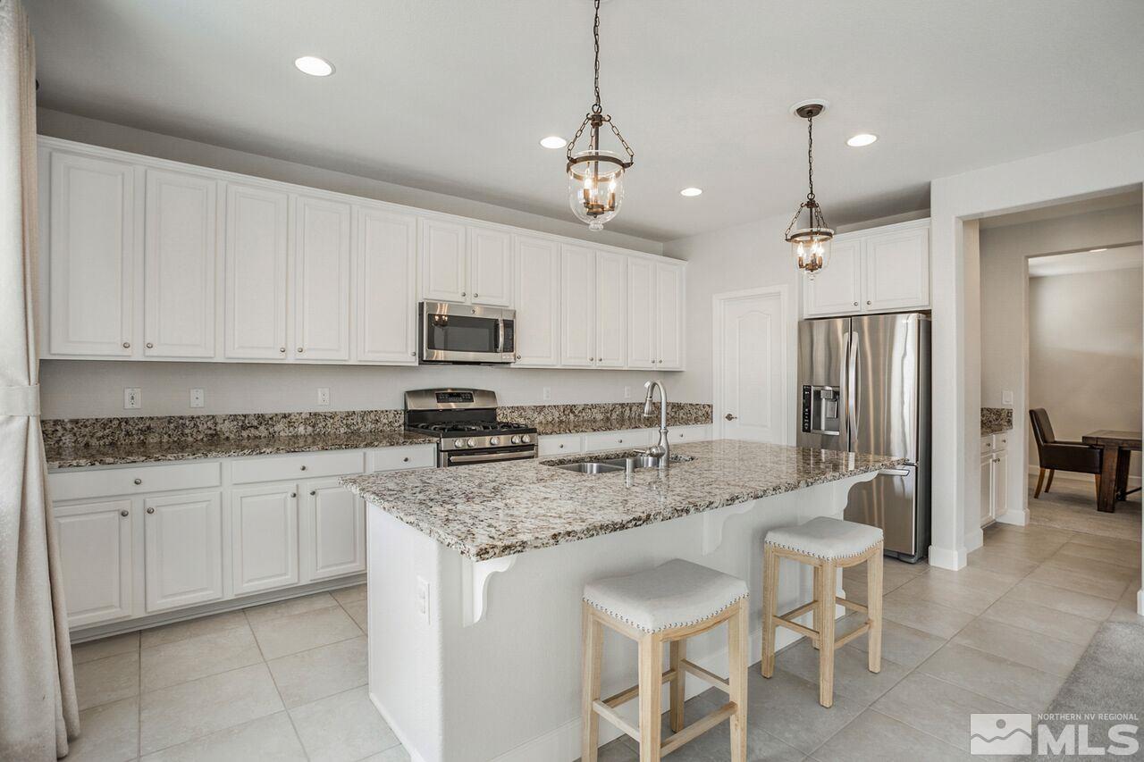 10370 Culiacan Pass Trail Reno, NV 89521 - Photo 9 of 25 a kitchen with stainless steel appliances granite countertop a stove top oven a refrigerator a sink and a island