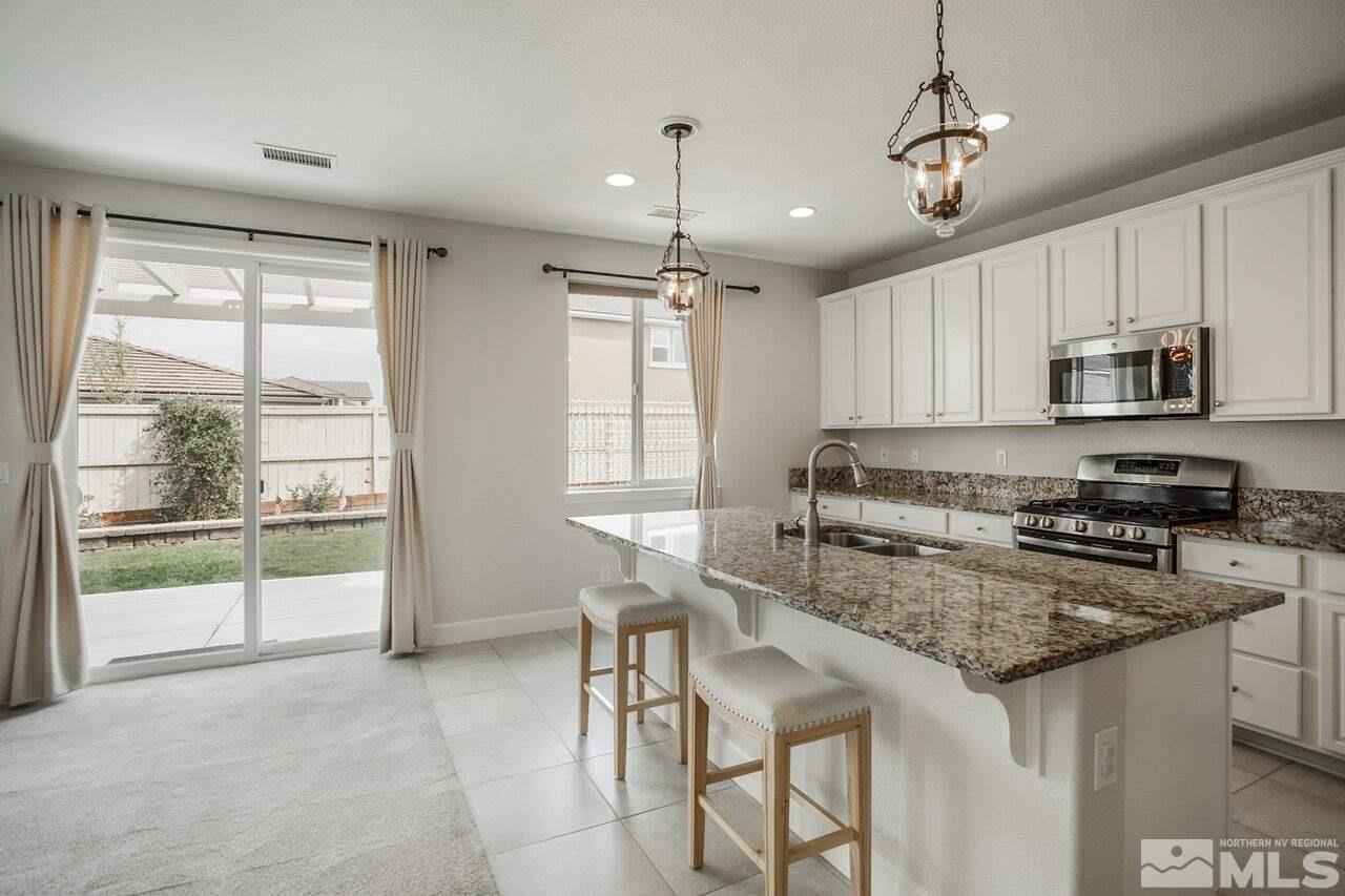 10370 Culiacan Pass Trail Reno, NV 89521 - Photo 10 of 25 a kitchen with stainless steel appliances granite countertop a stove top oven a sink a dining table and chairs