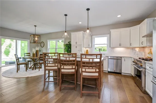 a kitchen with stainless steel appliances a dining table chairs stove and white cabinets