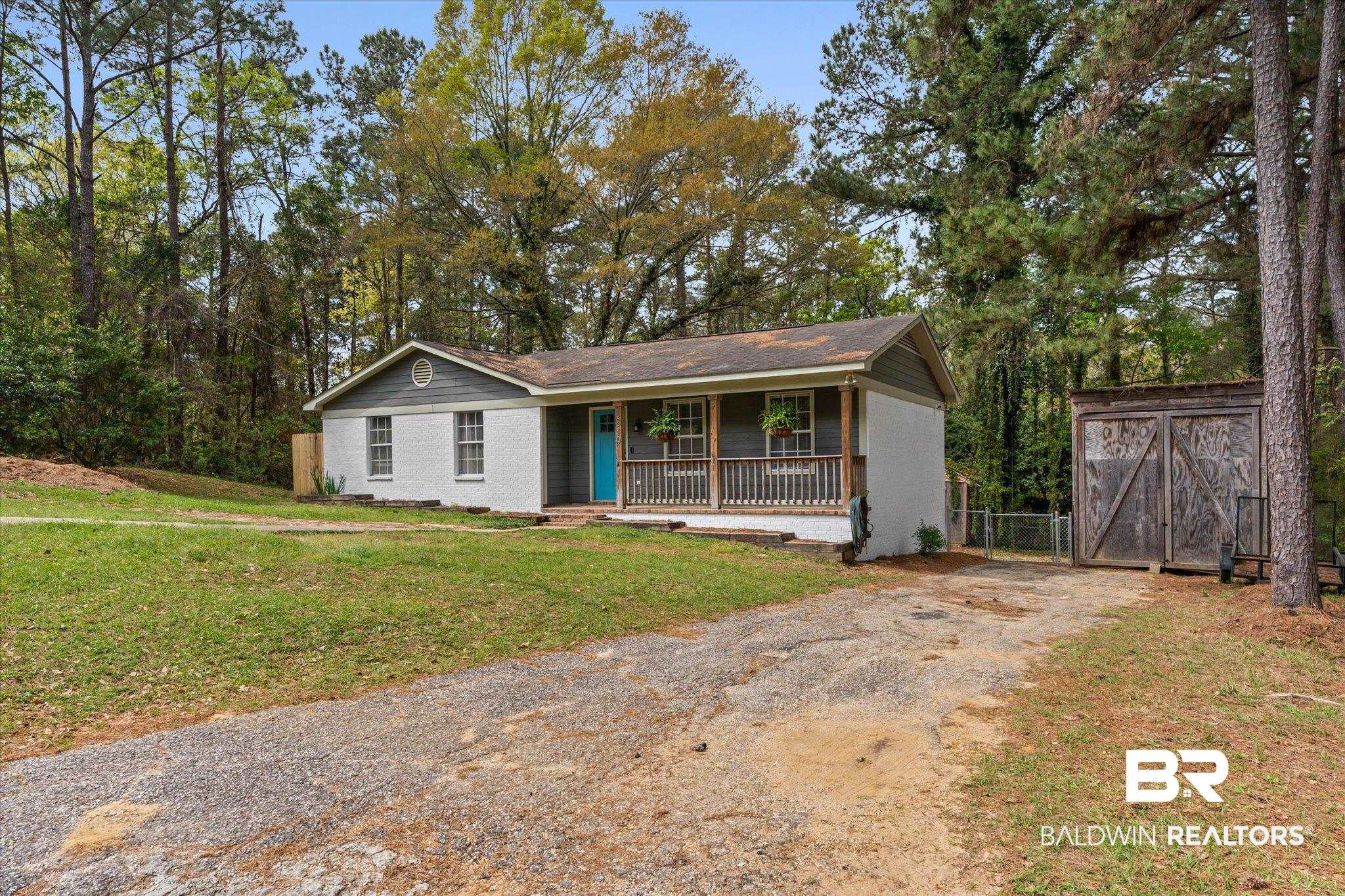 1849 Ranch House Drive Semmes, AL 36575 - Photo 22 of 23 Ranch-style home with covered porch, driveway, view of scattered trees, crawl space, and a gate